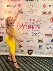 Smiling Dr Jennifer Murdock holding big background banner of Top 30 influential women of Houston 2022